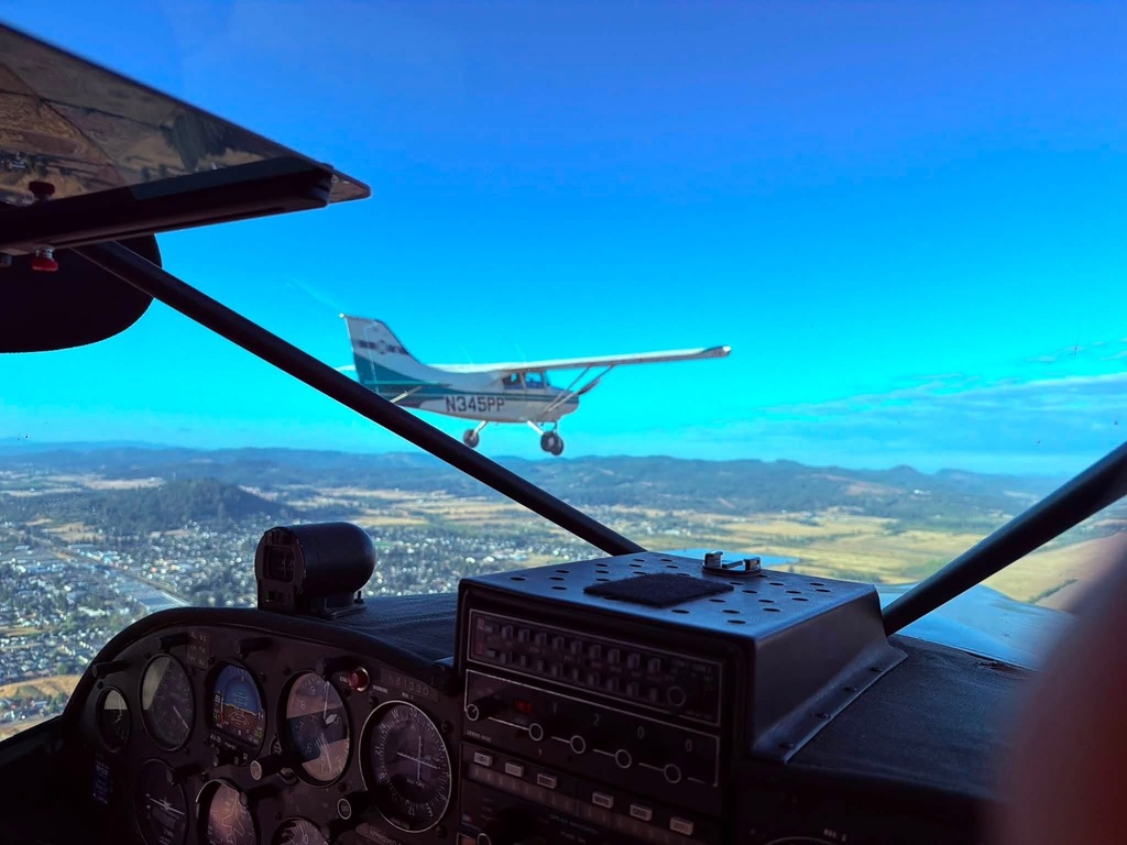 An image from the cockpit of one of the STOL planes as another STOL plane flies beside it. 