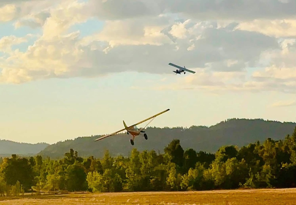 Image of two airplanes flying in the sunset during the Creswell STOL'n Out West event