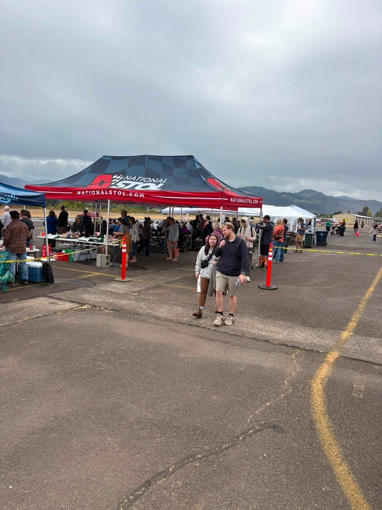 Image of event-goers gathering under the National STOL tent