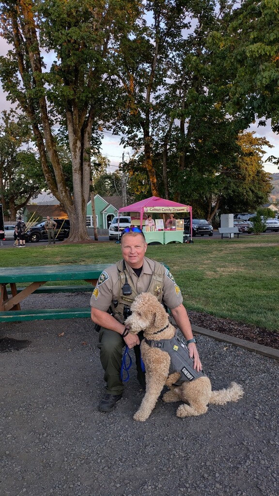 Image of Lane County Sheriff's Office Deputy Kendrick next to Corporal Carlton, the labradoodle that serves as the organization's Emotional Support Dog.