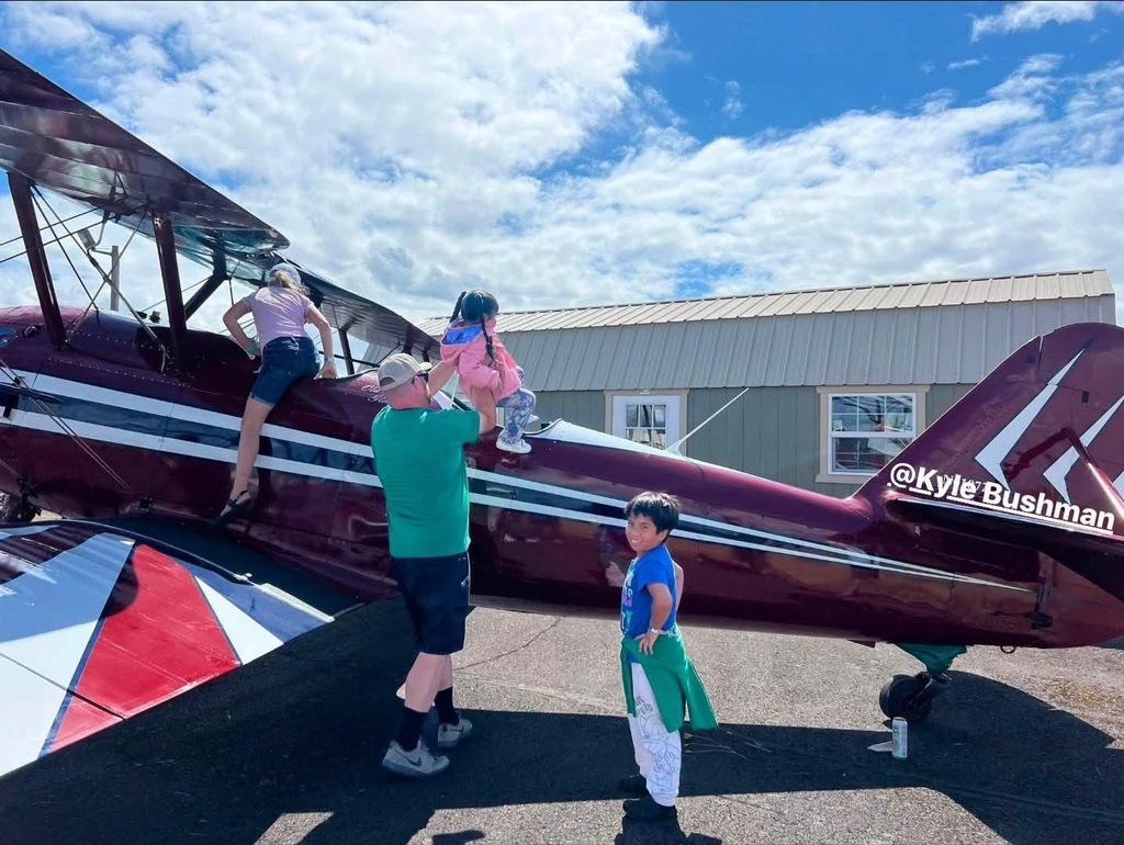 Image of Creswell Airport user Kyle Bushman letting three children climb in his airplane at the Creswell STOL  event.