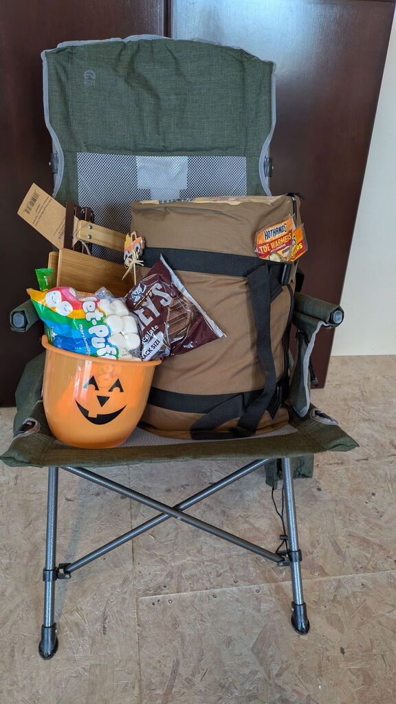 An image of the "Happy Camper" Deluxe Prize Package, which includes a camping chair, a sleeping bag, and supplies for making s'mores!