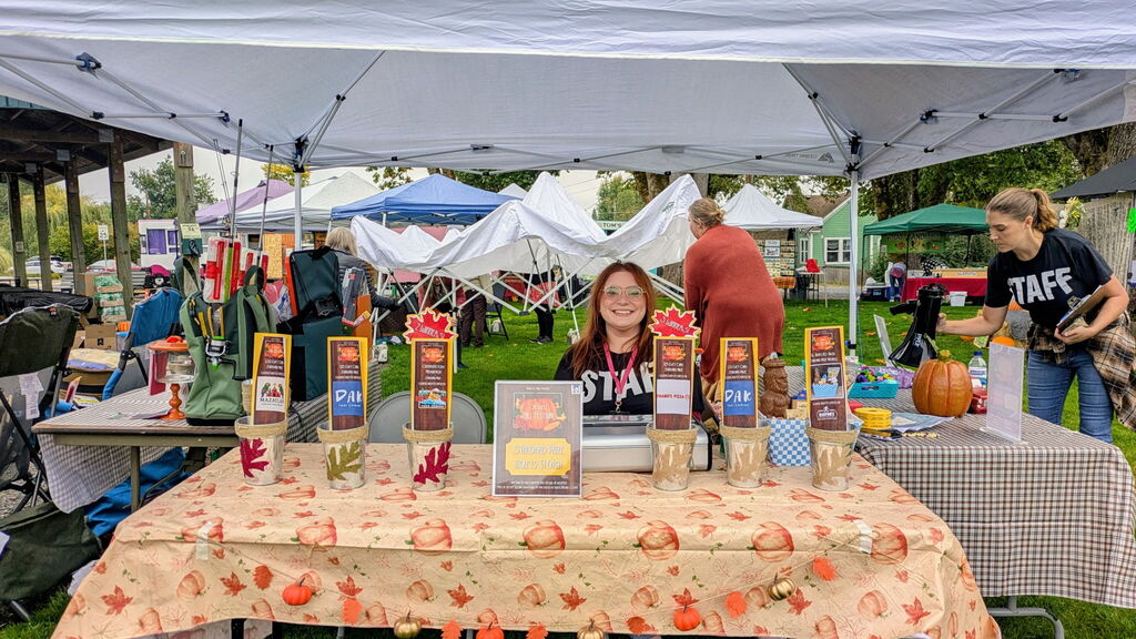 Image of City of Creswell Administrative Assistant Heather Prociw with some of the raffle prizes at the Creswell Fall Festival