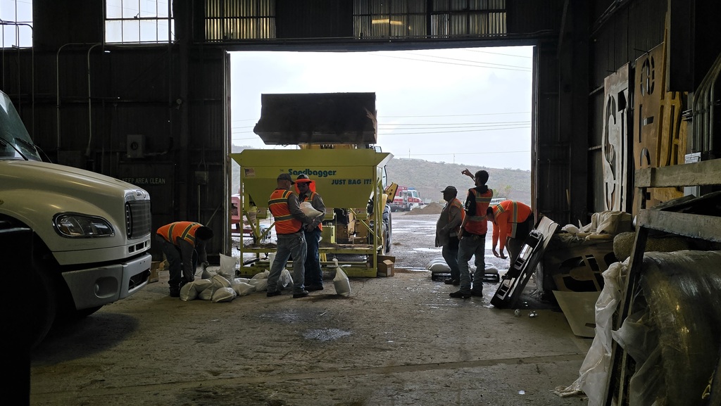 Staff filling sandbags under cover from the rain