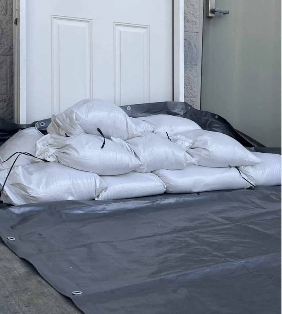 Example of stacked sand bags with plastic sheeting behind them in front of a white door