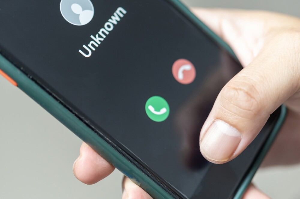 Image of someone holding a cell phone that says unknown on it