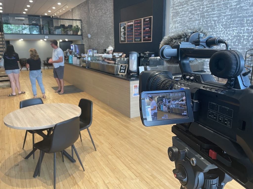 Wide shot of the inside of V's Deli with a video camera in frame