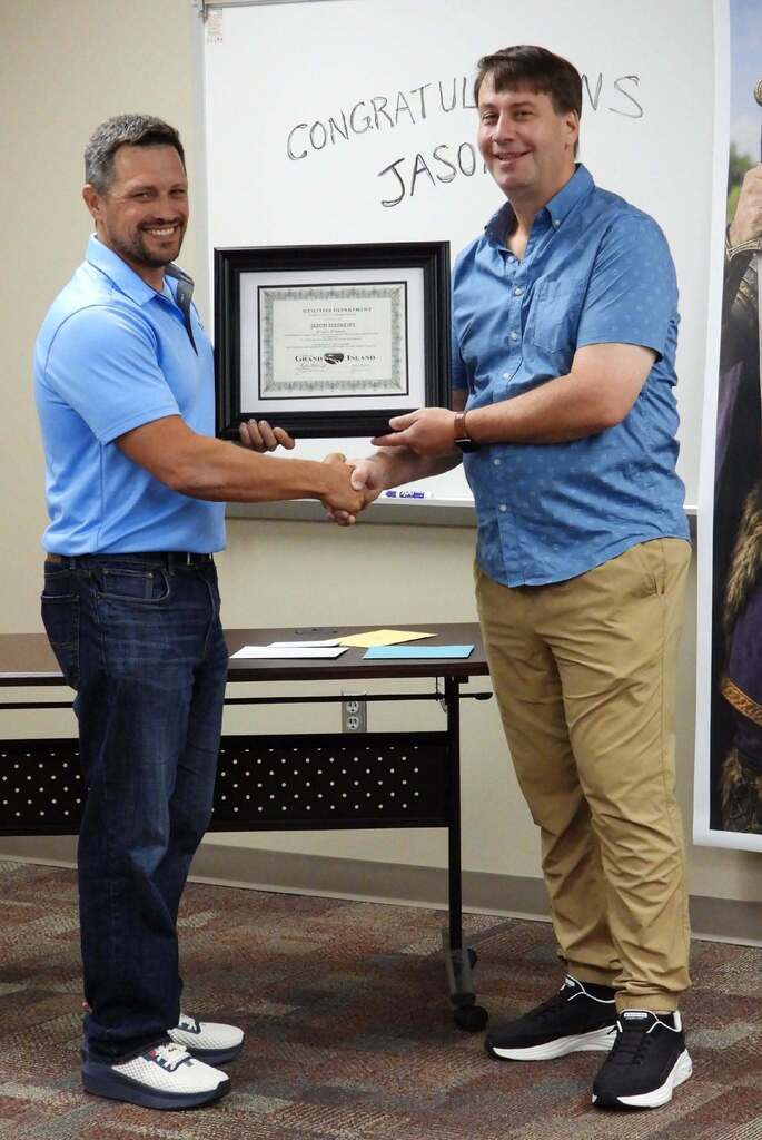 Photo of Jason Mathews shaking hands with Utilities Director Ryan Schmitz