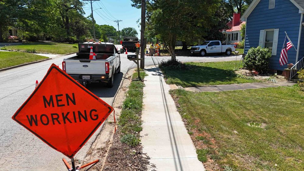 Men working sign with trucks and men working on sidewalk