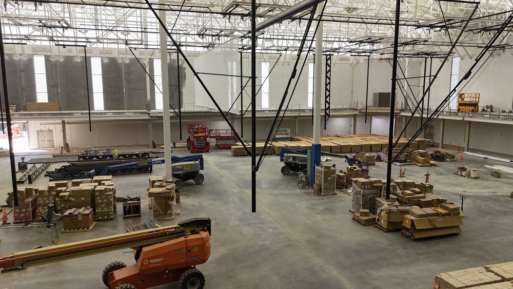 Wide shot of a gym under construction with large piles of wood spaced throughout