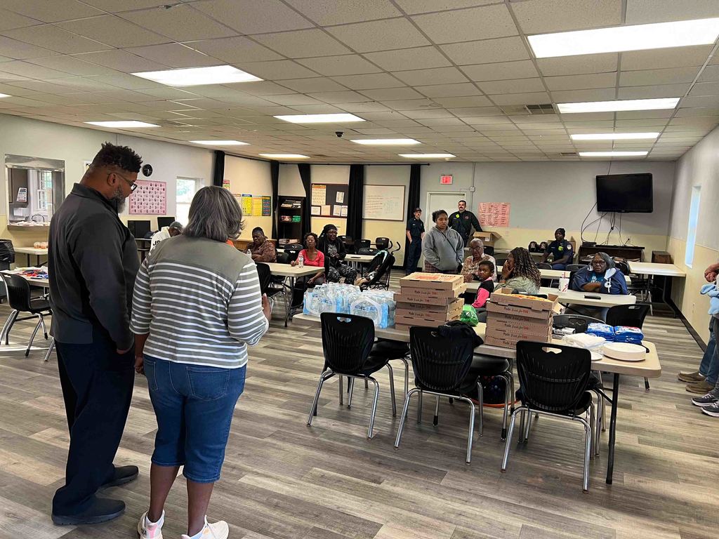 National Night Out at the Needmore Center - Shot of Room with Families Sitting and Eating Pizza