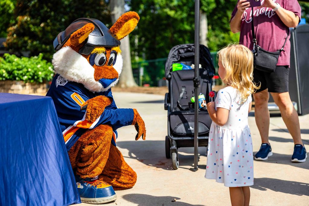 Stomper from the Greenville Swamp Rabbits Kneels Next to Little Girl