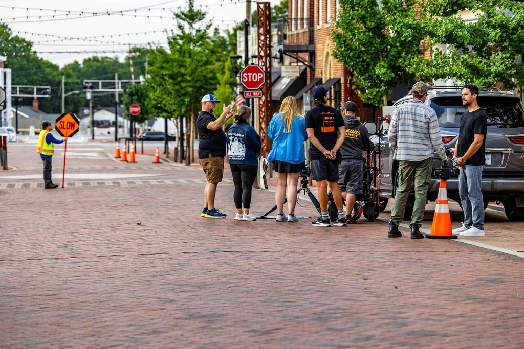 a filming crew discusses a shot on trade st