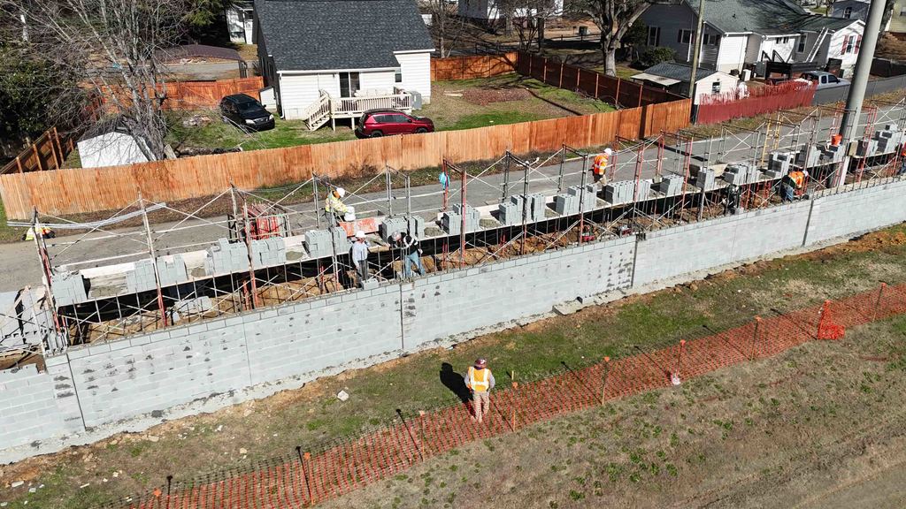 Drone shot of construction workers assembling a concrete block wall