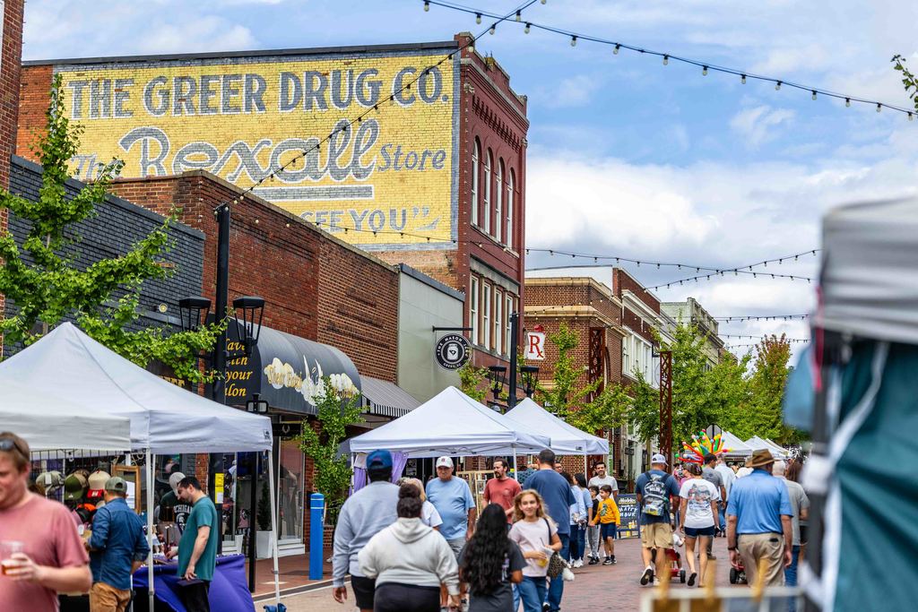 Shot of Downtown Greer on Trade Street during an event with a crowd of people walking down the street and stopping at vendor tents