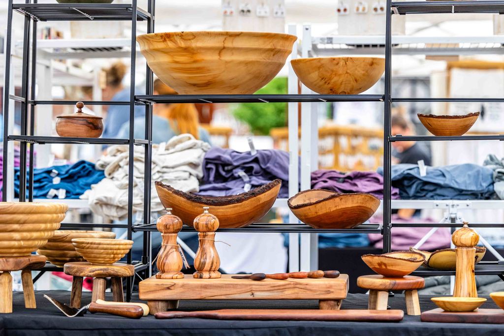 Shot of multiple wooden bowls, salt and pepper shakers, and other various wood working products at a vendor table 