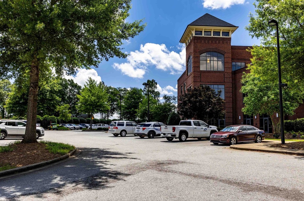 An image of a parking lot with a few cars and a building with tower in the back to the right