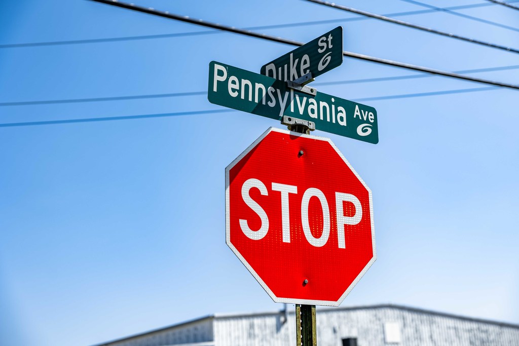 A stop sign with the street names Pennsylvania Ave. and Duke St. against a blue sky