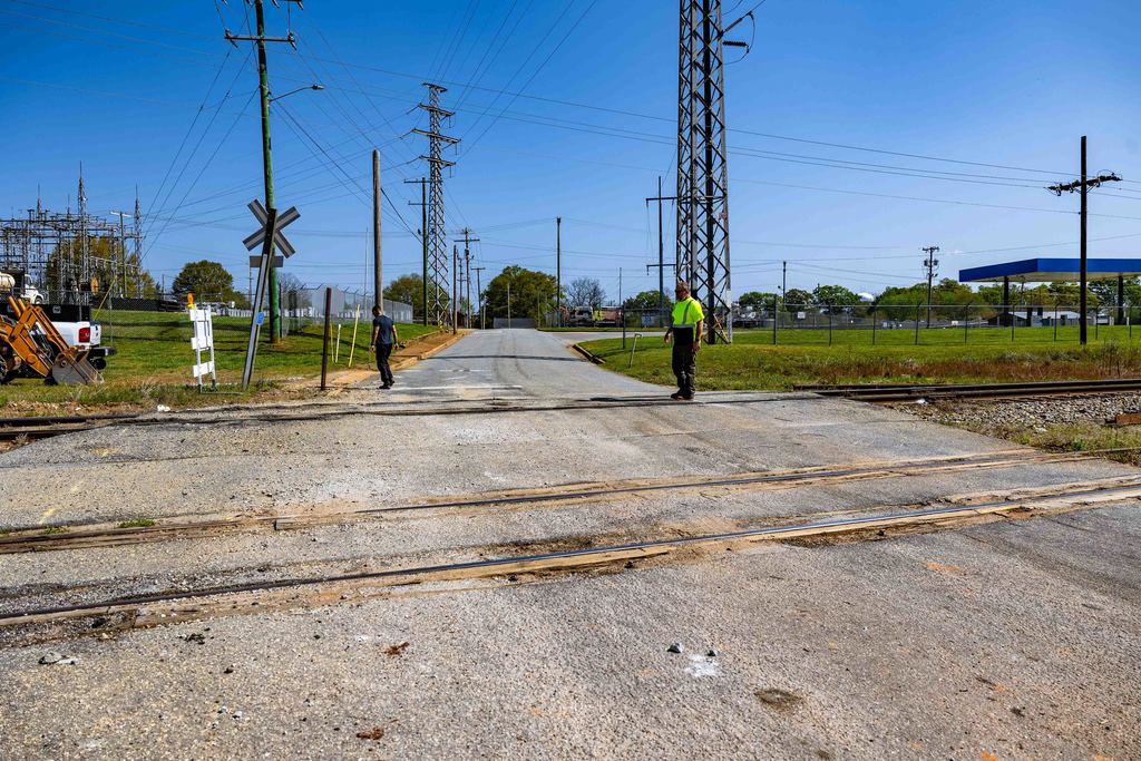 Shot of a road with railroad tracks going across it with two maintenance workers standing on the road