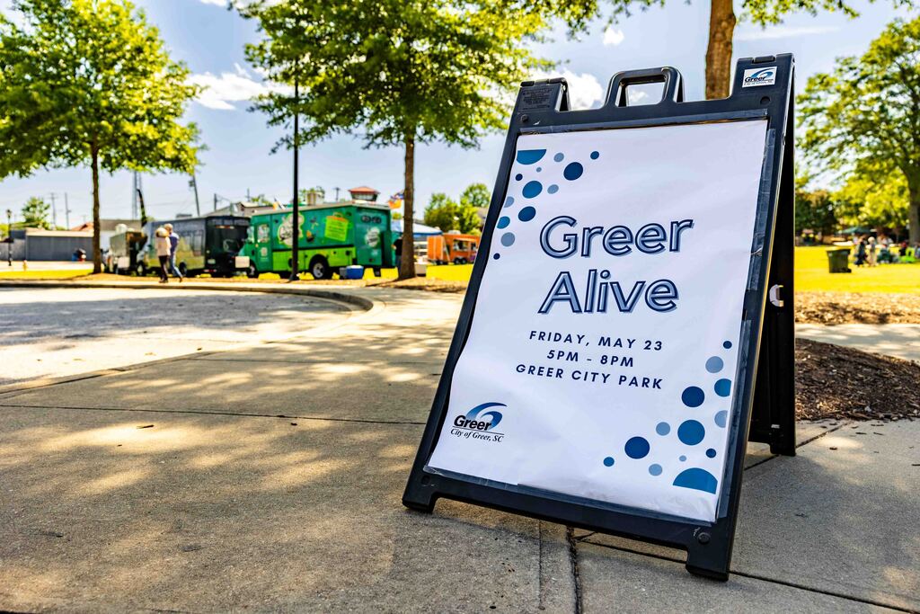 photo shows a Greer Alive sign and food trucks in the circle drive at Greer City Park