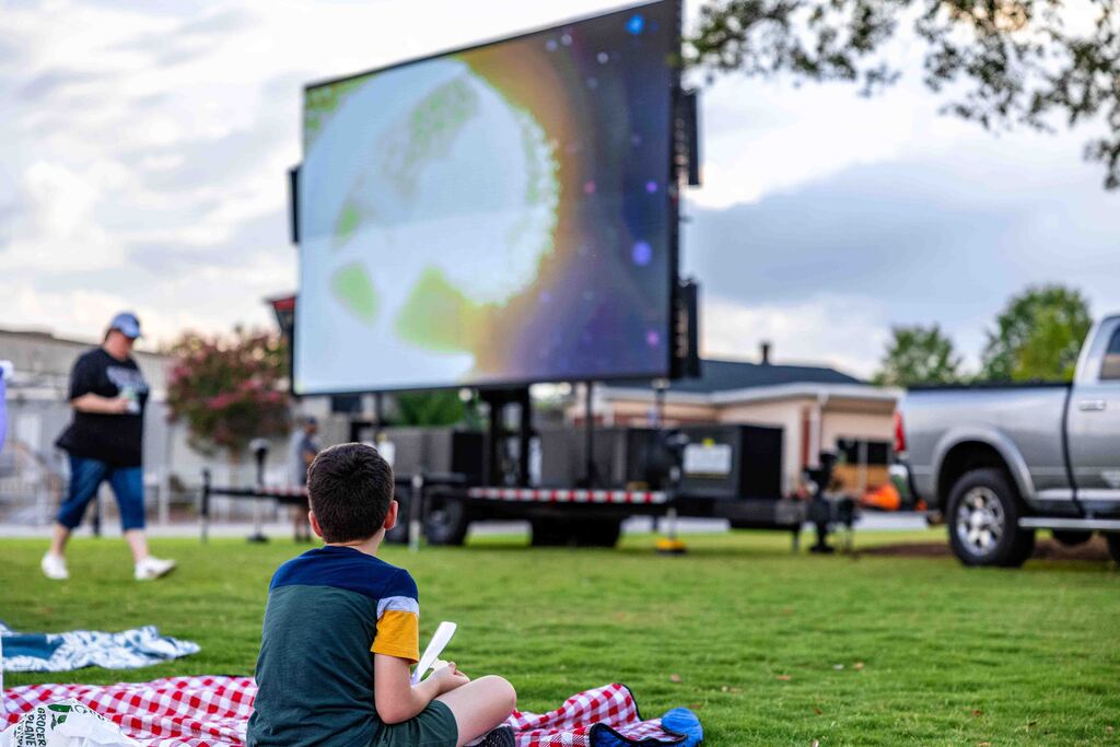 Kid looks up at large screen in park