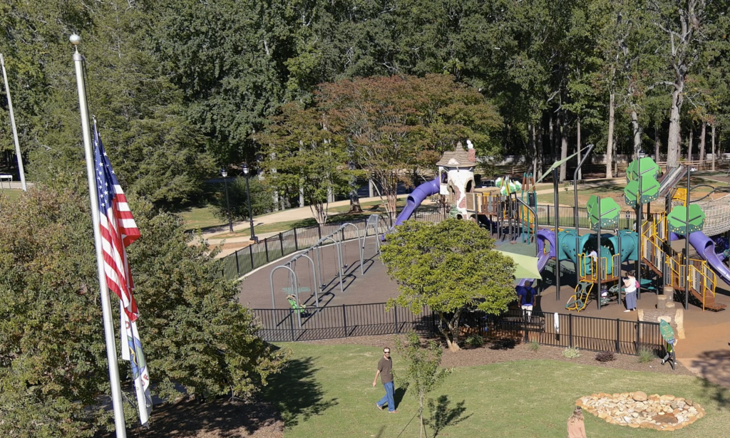 Picture shows an aerial view of Kids Planet at Century Park with an American flag in the foreground and playground equipment in the background