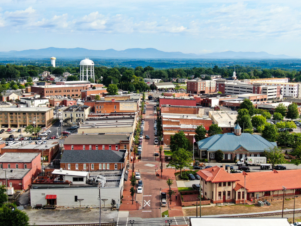 Drone shots of downtown Greer buildings with mountains and blue sky in the background