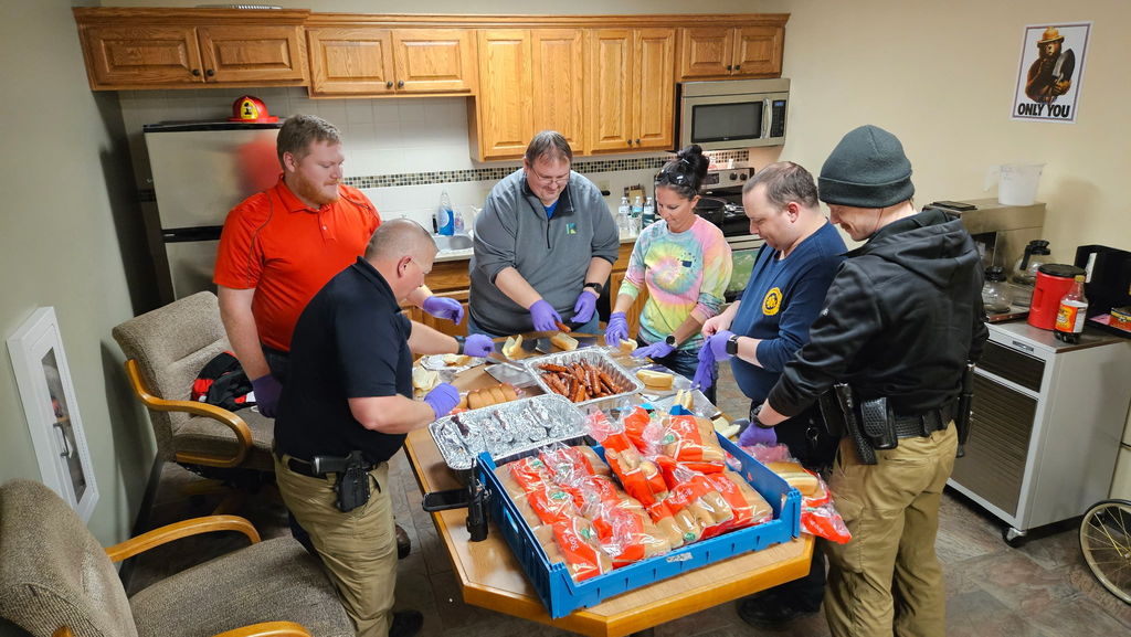 group of people assembling hot dogs to eat