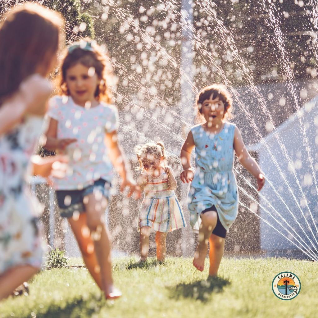 kids playing in the sprinkler in sunshine