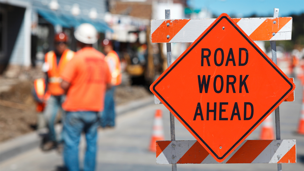 Construction workers with Road Work Ahead sign