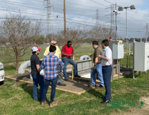 Group of six people gathered around an outdoor wastewater lift station