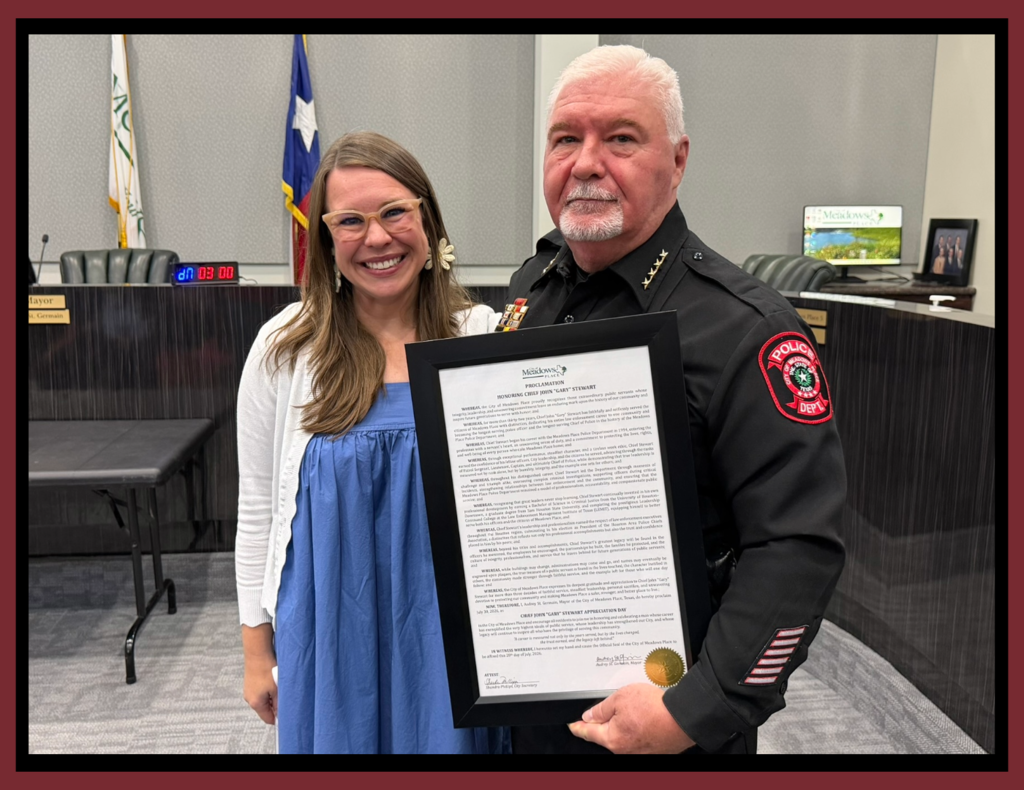 **Alt text:** Photo of Mayor Audrey St. Germain presenting Police Chief Gary Stewart with a framed proclamation during a City Council meeting. Chief Stewart, wearing his Meadows Place Police Department uniform, holds the proclamation recognizing his retirement and years of service while standing beside the Mayor in the Council Chambers.