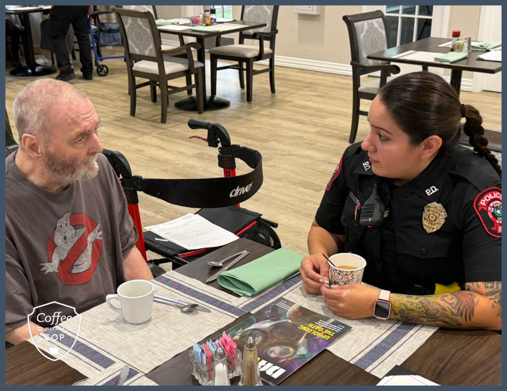 A Meadows Place police officer and a resident sit across from each other at a dining table, sharing a conversation during Coffee with a Cop at The Jasper of Meadows Place.