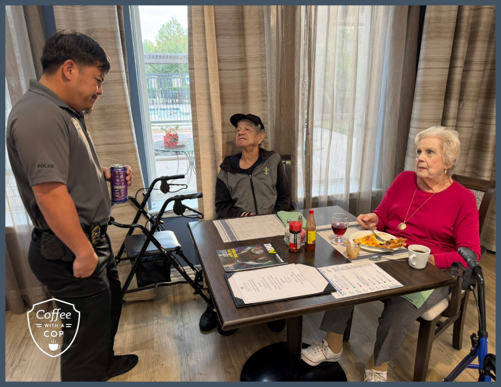 A Meadows Place police officer talks with two residents seated at a dining table during Coffee with a Cop at The Jasper of Meadows Place.