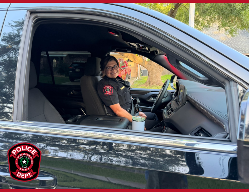 Meadows Place police officer smiles from the driver’s seat of a police vehicle.