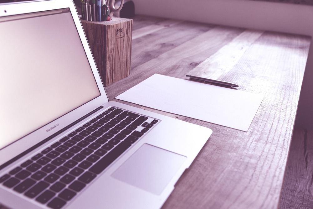 A laptop and paper with pen
