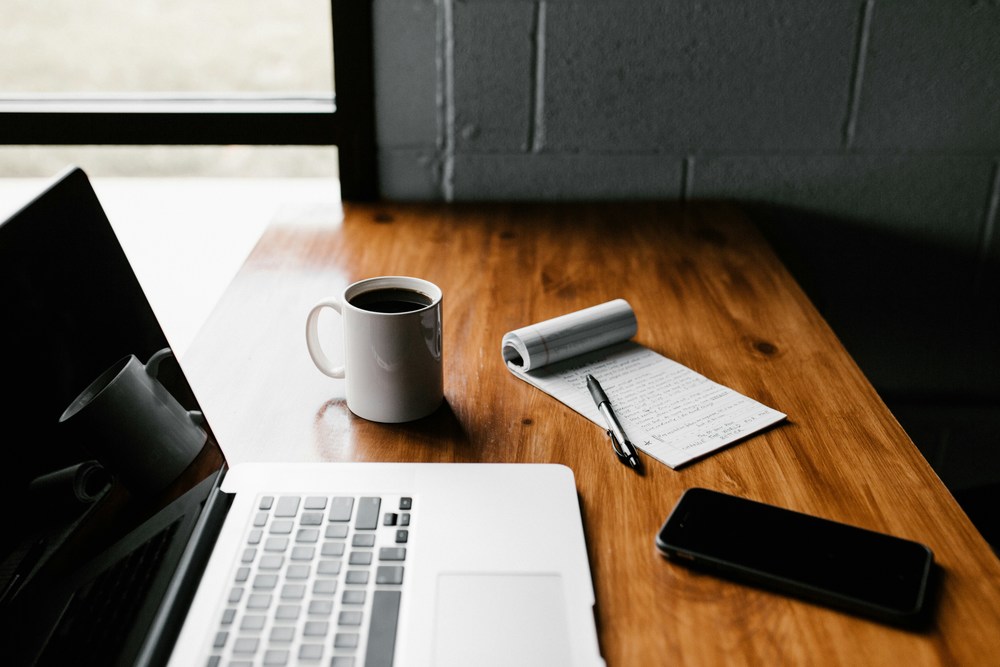Laptop, coffee, and phone on a work desk