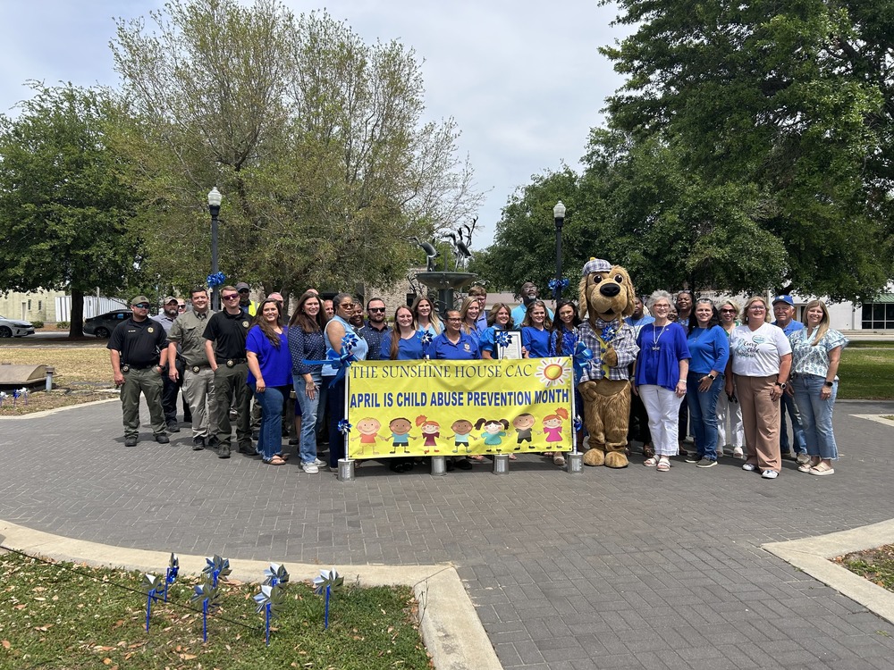 2026 Child Abuse Prevention Month - People standing behind banner taking a picture infront of fountain 