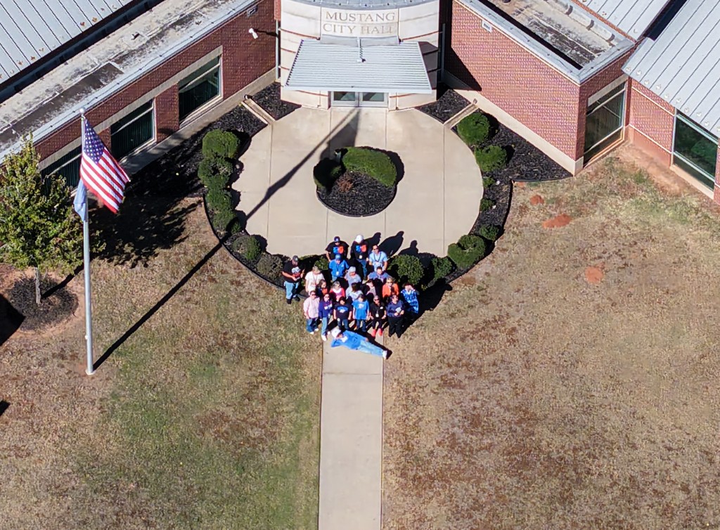 An aerial photo of Mustang City Hall with its employees decked out in OKC Thunder gear