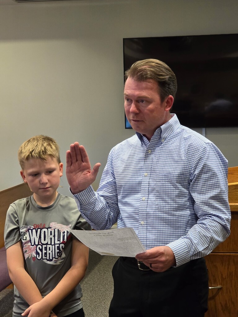 Councilman Jesse Bratton receiving the oath of office accompanied by his son Beckham