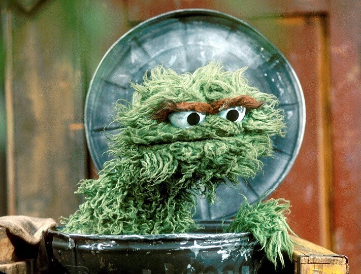 A photo of Oscar the Grouch - a green muppet with bushy eyebrows