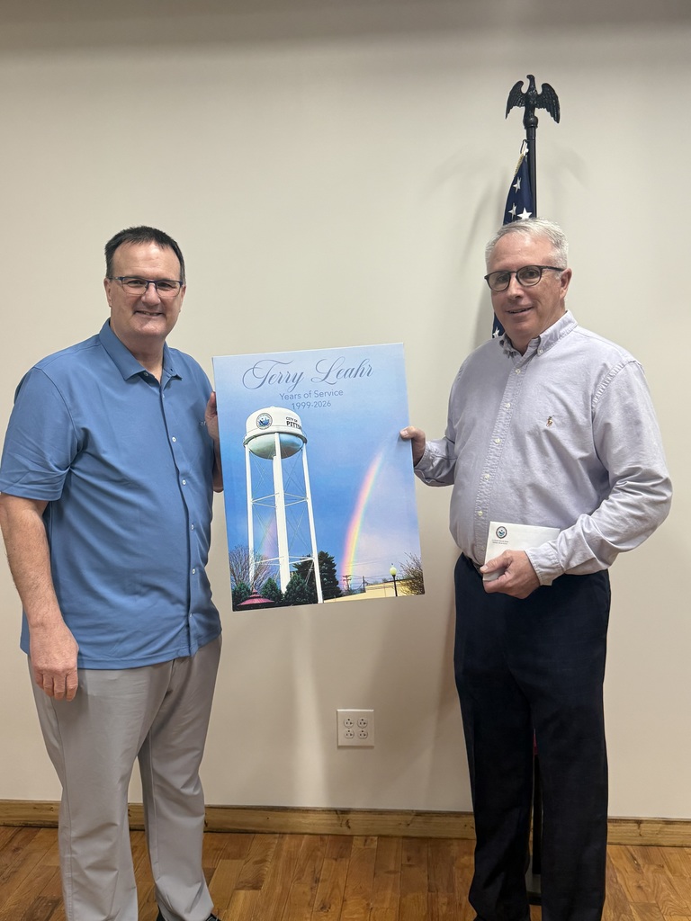 Terry Leahr retirement party photo of Mayor Mendenhall handing Terry Leahr a canvas of a the City water tower with a double rainbow in the back ground.