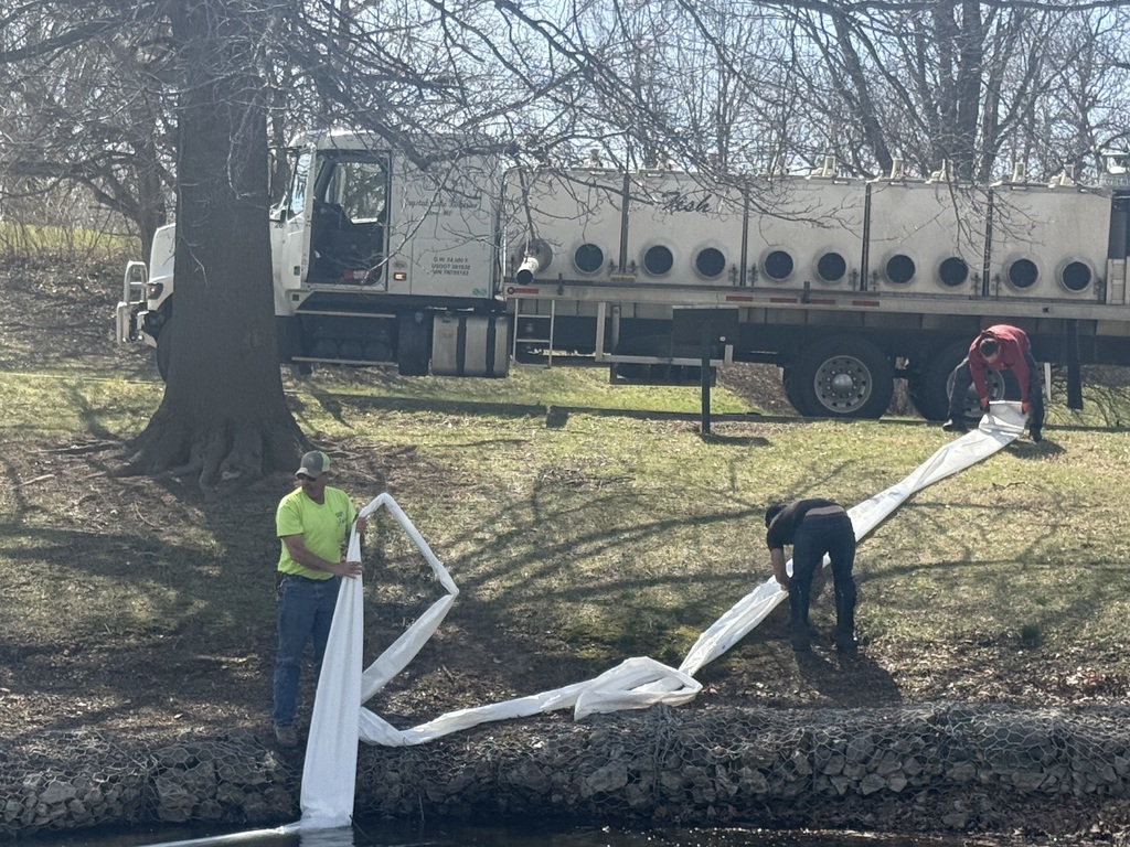 City worker Kenny assisting Crystal lake fisheries in putting trout into the king park lagoon