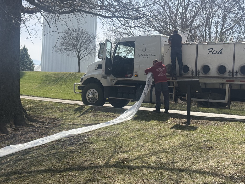2 workers from crystal lake fisheries hooking up the tube to dispense the fish