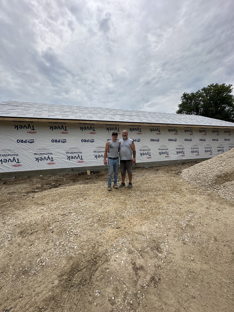 austin and allen motley standing in front of a house they built