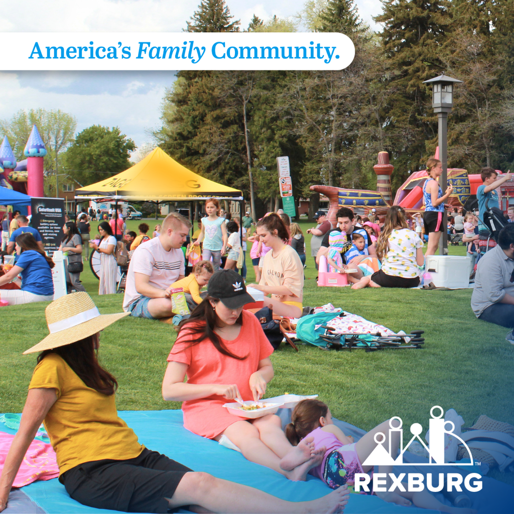 Lots of people on the lawn of Porter Park, some event tents and bounce houses in the background, people lounging on blankets, sitting in small groups, etc. at an event in the Park
