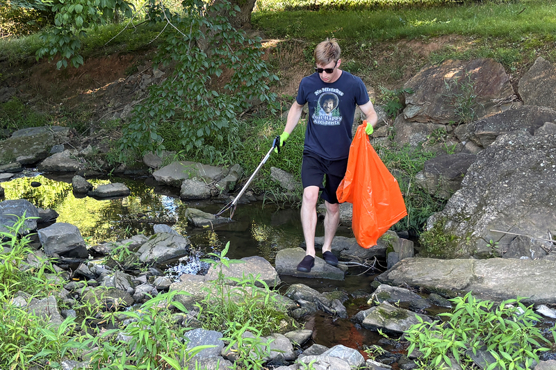 Volunteer collecting trash from the creek