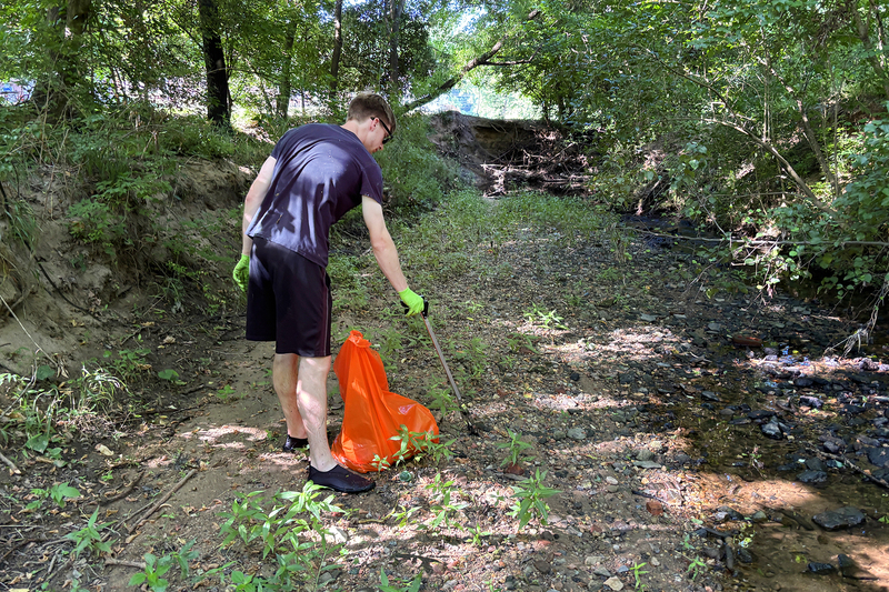 Volunteer collecting trash from the creek