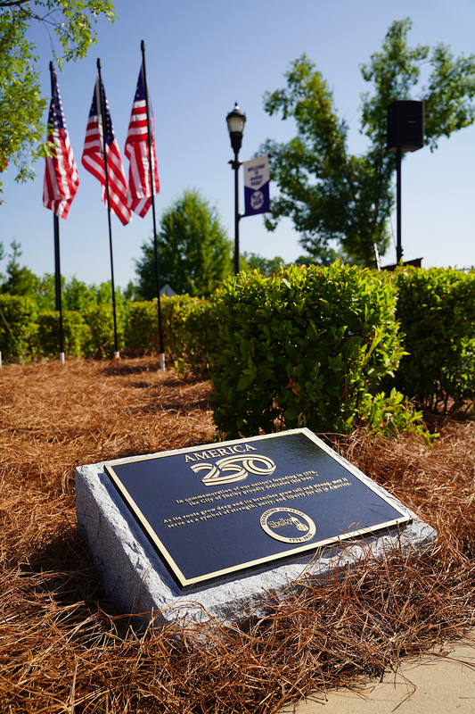 The bronze plaque with flags and trees in the background