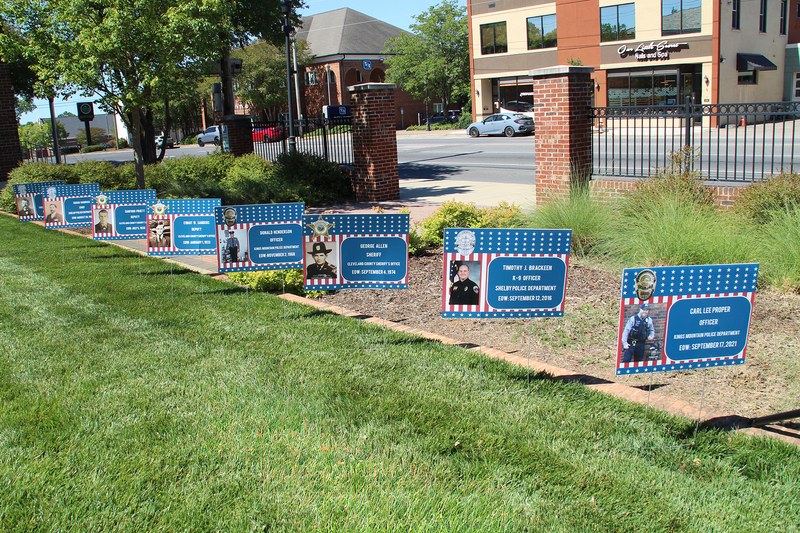 Yard signs with names, pictures, and end of watch dates for fallen officers